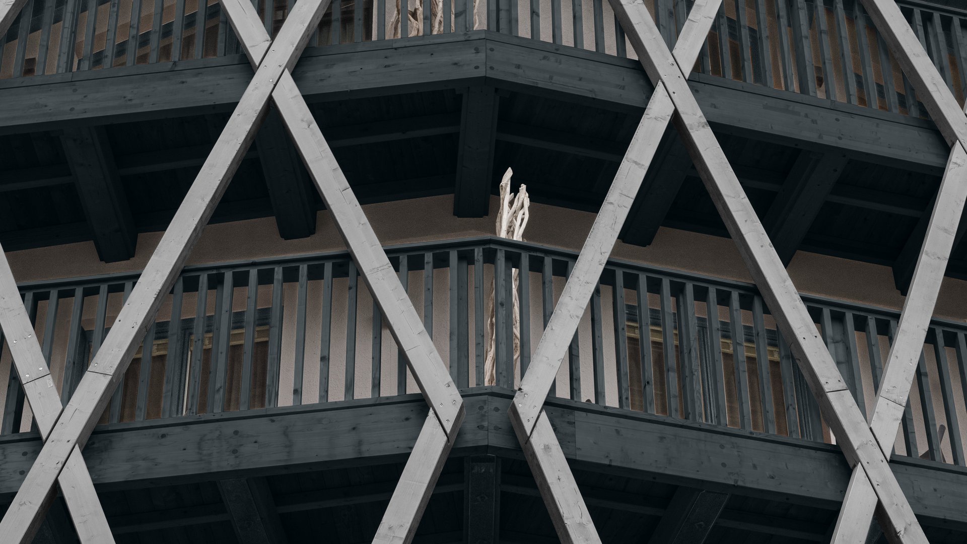 Ihr Hotel in St. Anton am Arlberg Fassade eines Hauses mit markanten diagonalen Holzbalken und Balkonen