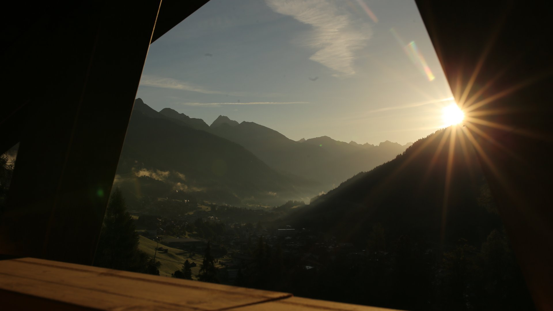 Ihr Hotel in St. Anton am Arlberg Sonnenaufgang über Bergen von einem hölzernen Fensterrahmen aus