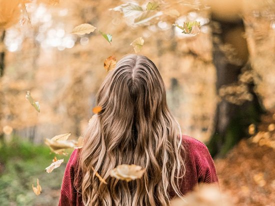 Winter hiking at Mt Arlberg Woman with long blonde hair and red sweater in autumn forest with falling leaves