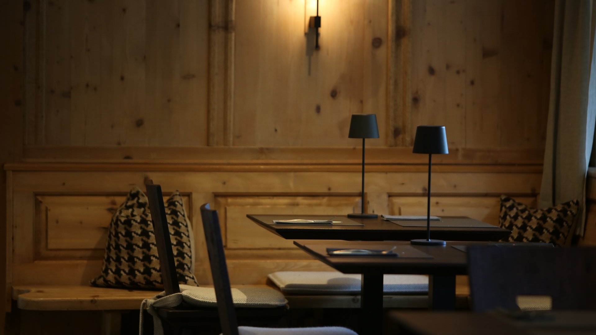 Ihr Hotel in St. Anton am Arlberg Gemütliche Holzecke mit Tischlampen und gepolsterten Stühlen in Restaurant