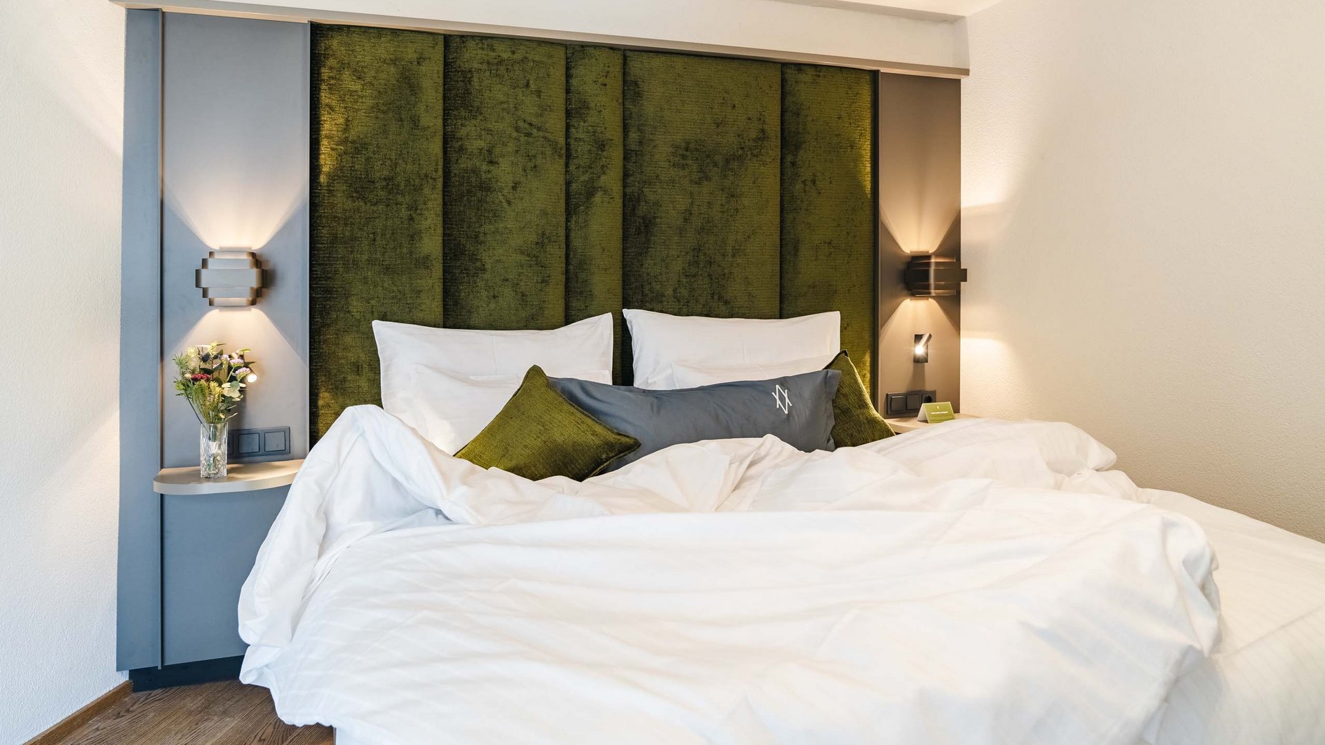 Ihr Hotel in St. Anton am Arlberg Modernes Schlafzimmer mit grünem Kopfteil und weißer Bettwäsche