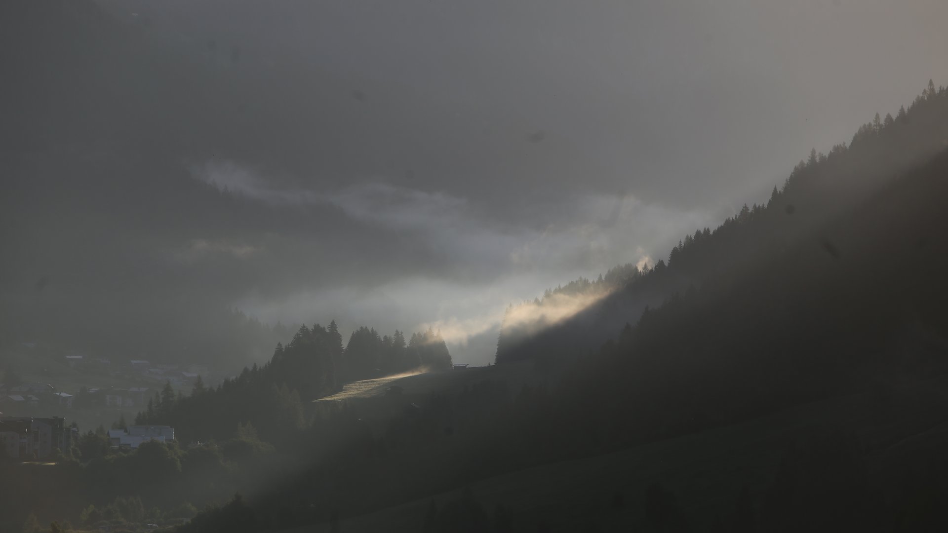 Ihr Hotel in St. Anton am Arlberg Sonnenlicht durch brüchige Wolken über bewaldeten Hügeln