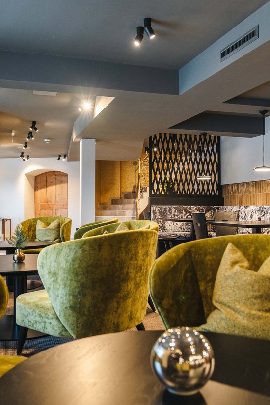 Ihr Hotel in St. Anton am Arlberg Modernes Café mit grünen Samtsesseln und runden Tischen