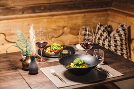 Reine Urlaubsfreude in Ihrem Hotel in St. Anton Elegantes Dinner mit Wein, Pasta und Dekoration auf Holztisch