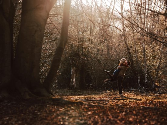 Adventure in harmony with nature Couple embracing happily in autumn forest with sunlight filtering through trees